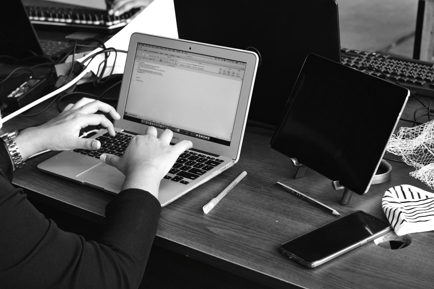 Hands typing on a silver laptop at a wooden desk.